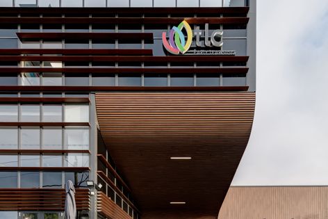 The Sculptform aluminium batten facade at TLC Whitewater by VIA Architects is complemented by rivergum wood-finish aluminium click-on cladding.